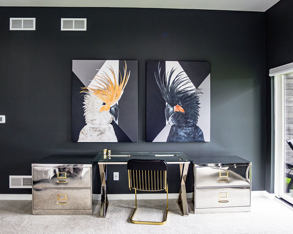 Modern black home office with mirrored desk, metallic accent cabinets, and bold cockatoo artwork