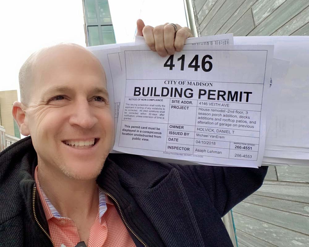 a happy man holding a building permit