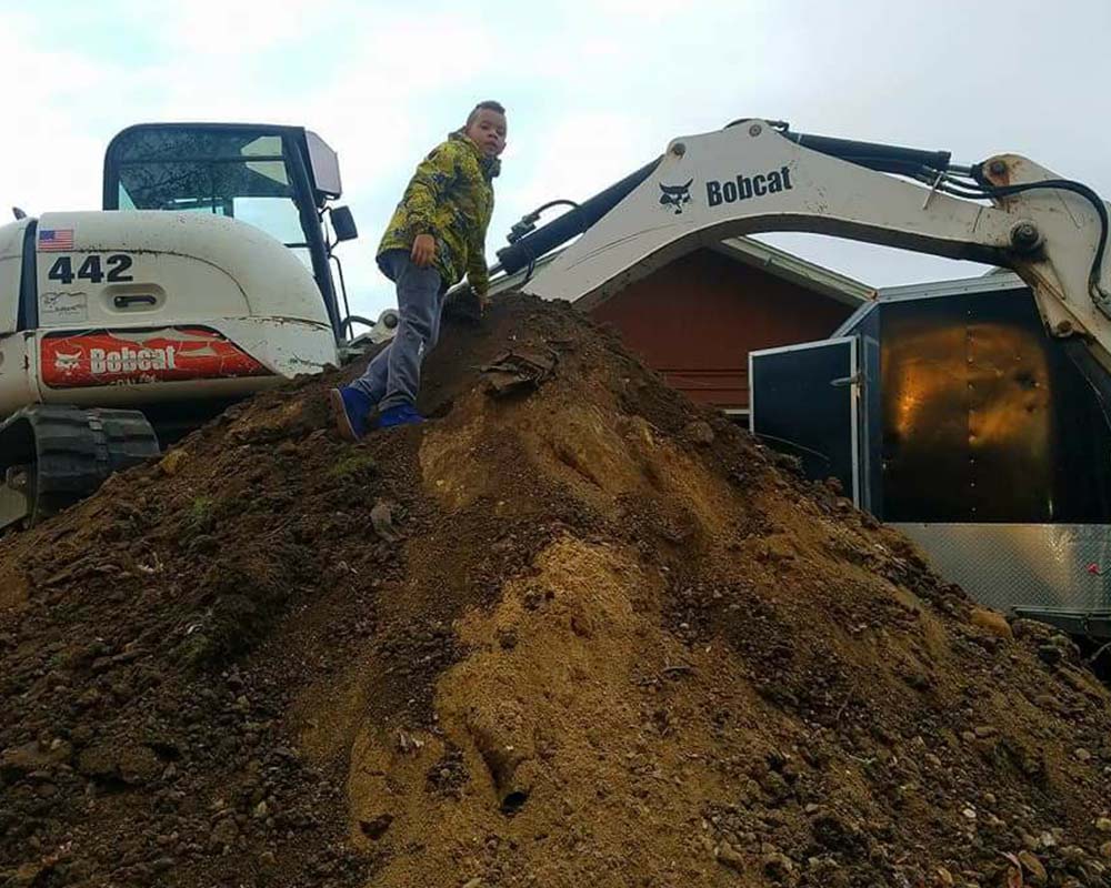 A child on a pile of dirt in a construction area