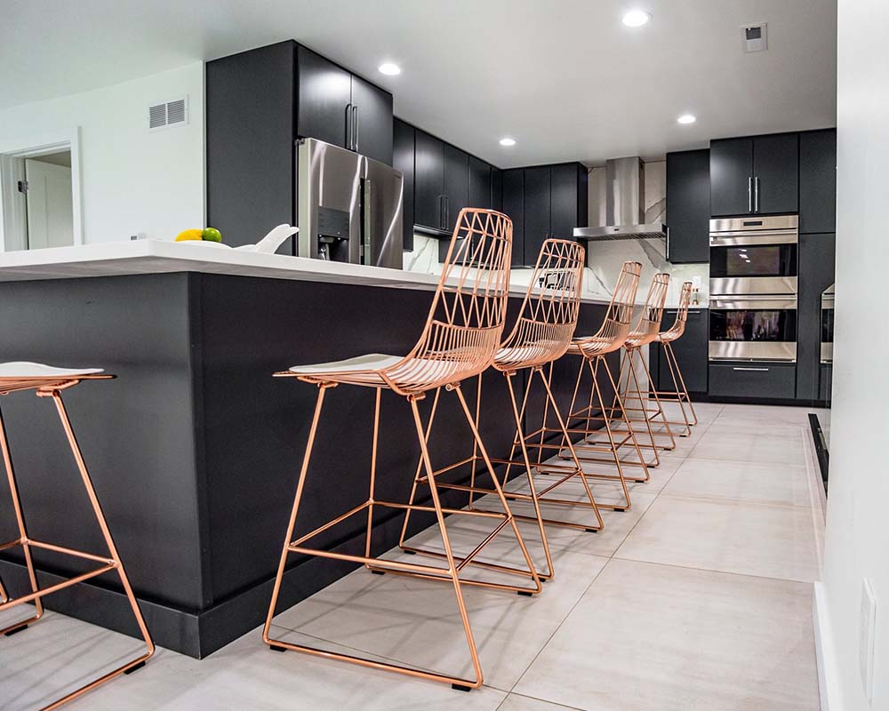 The updated kitchen with black cabinets and rose gold metal chairs