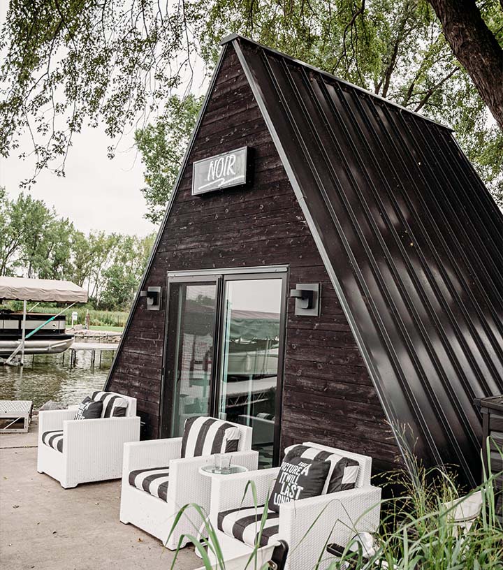 A view of the updated lake house with chairs outside of it