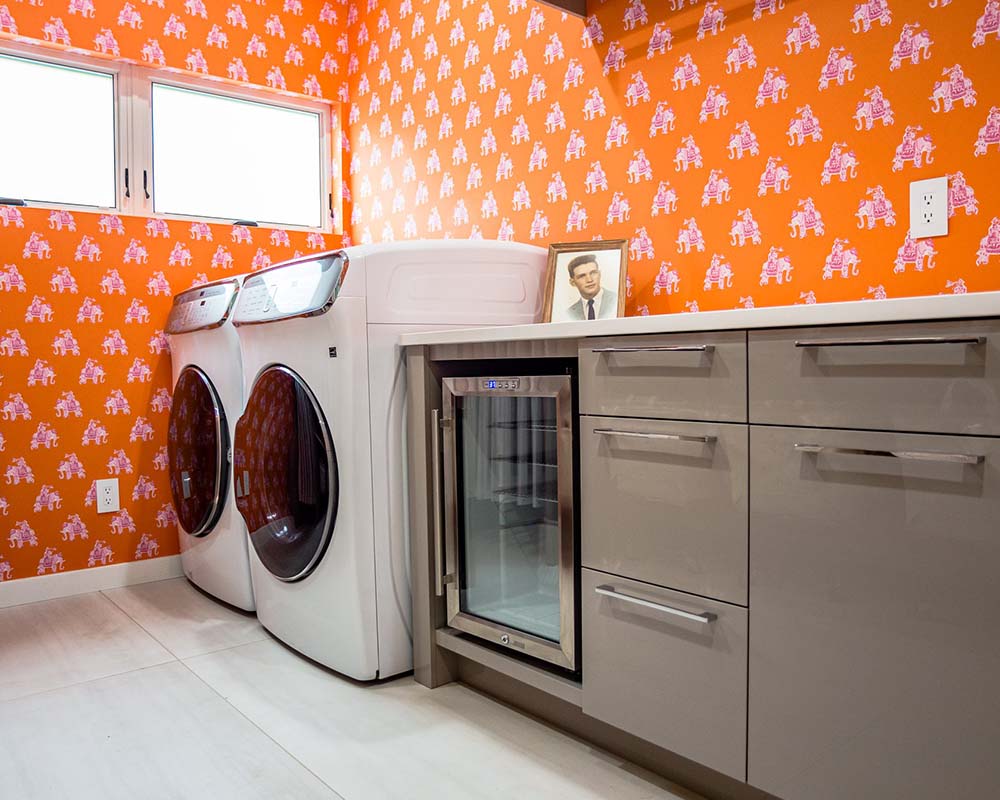 A laundry room with bright orange wallpaper