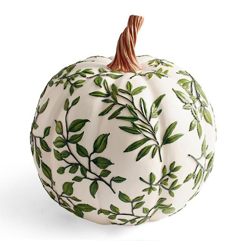 A fake pumpkin painted white with leaves all over it