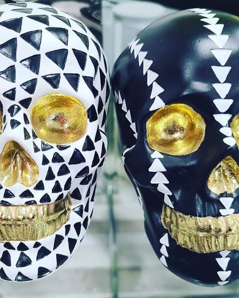Two fake skulls, one black and one white, both have gold accents