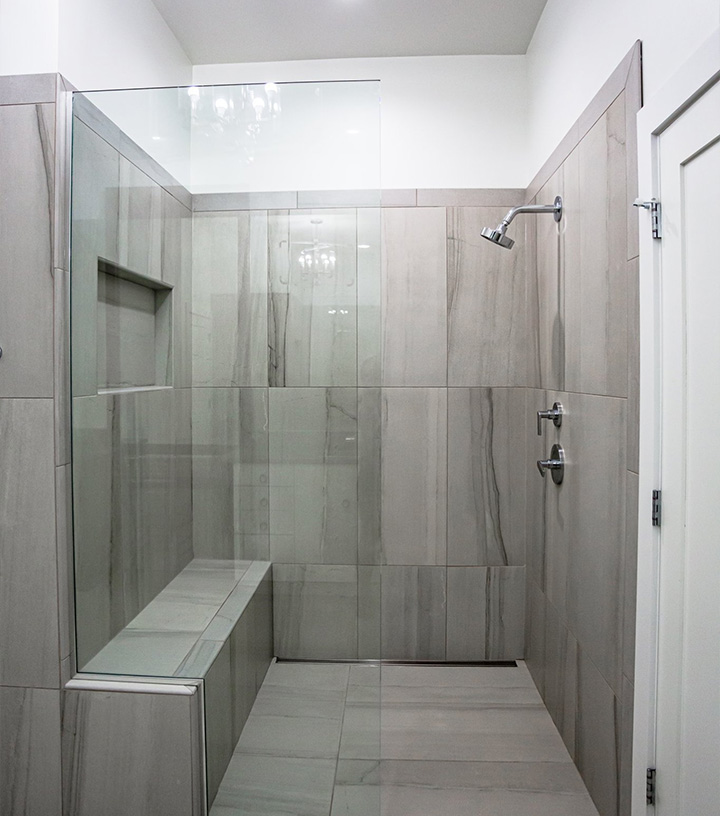 A bathroom shower with large grey tiles