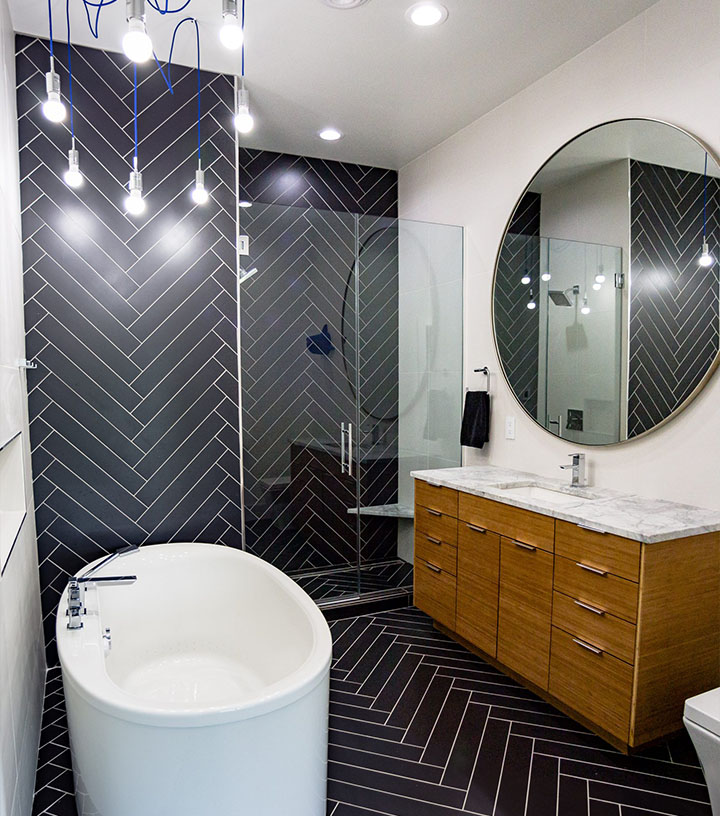 A bathroom shower with black tiles in a herring bone pattern