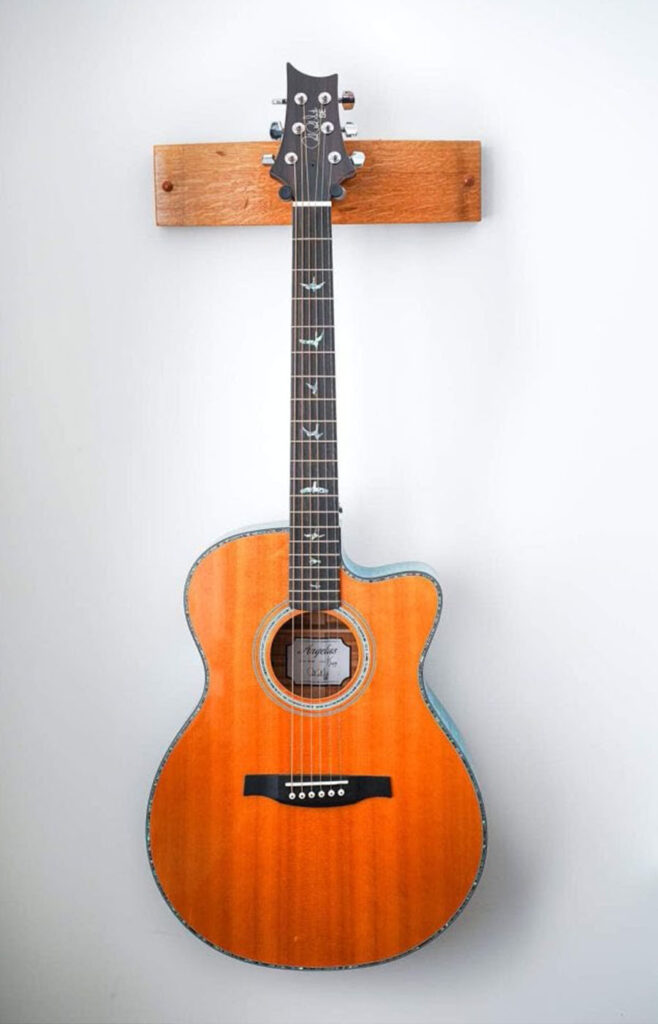 Acoustic guitar mounted on wall with natural wood finish and minimalist decor