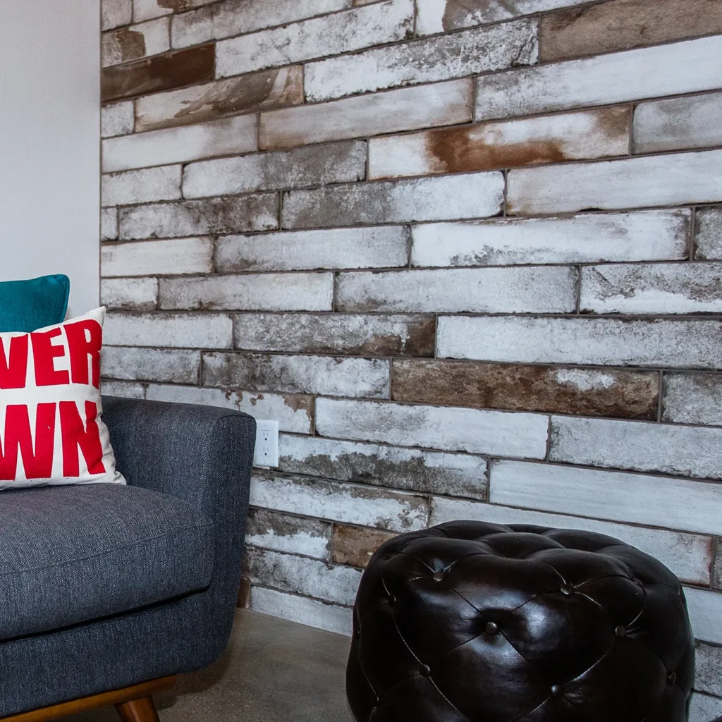 Modern accent wall with textured tile, gray lounge chair, and leather ottoman