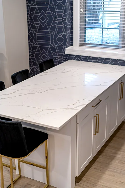 Modern white kitchen island with quartz countertop and black bar stools