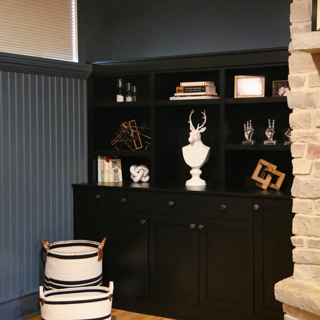 Modern black built-in shelving with decorative accents and stone fireplace detail