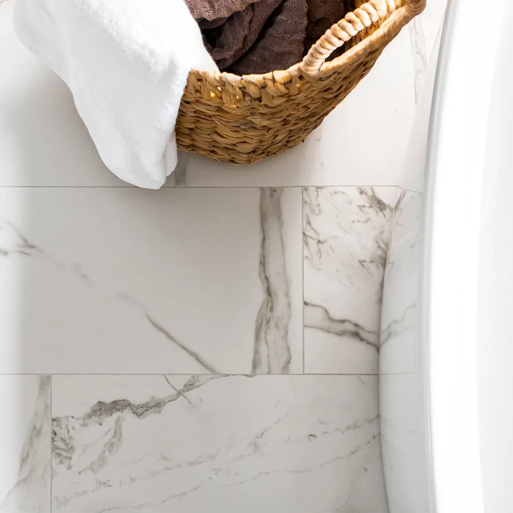 White marble tile flooring with woven basket and soft bath linens