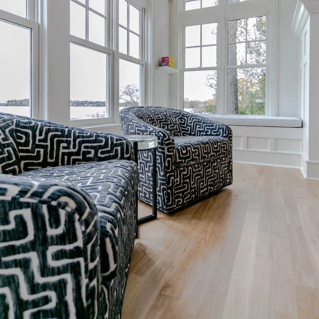 Modern patterned accent chairs in bright sunroom with large windows and hardwood flooring