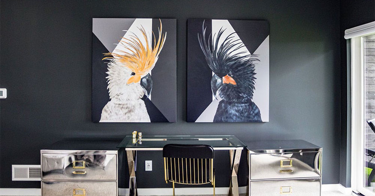 Modern black home office with mirrored desk, metallic accent cabinets, and bold bird artwork